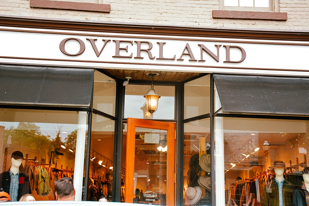 Storefront of Overland clothing store with visible window displays showing hats and jackets inside.
